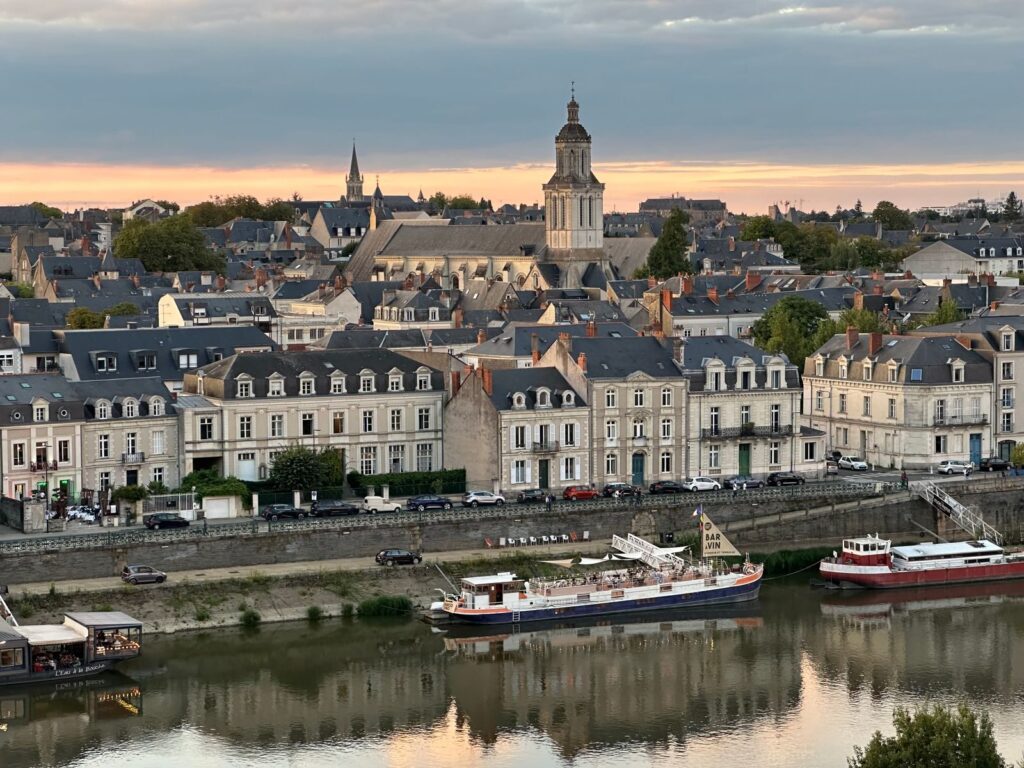 Historic cityscape of Angers, France, featuring charming architecture along the river at sunset.