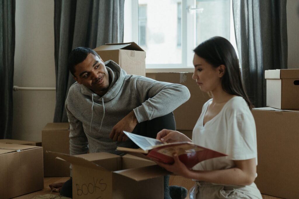 A couple exploring their new home while unpacking boxes and looking at a photo album.